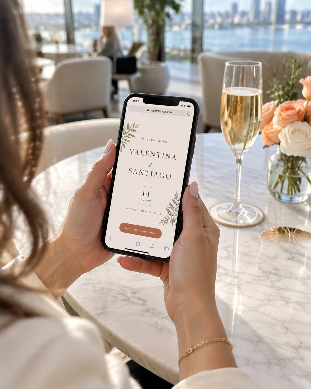 Manos sosteniendo un celular con una invitación digital de boda en una mesa elegante de hotel